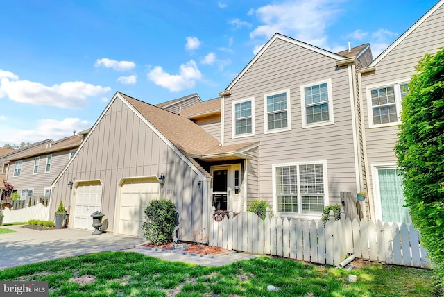 view of front facade with fence, an attached garage, a shingled roof, board and batten siding, and concrete driveway
