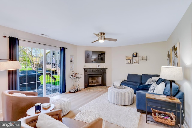 living room featuring visible vents, ceiling fan, wood finished floors, and a fireplace