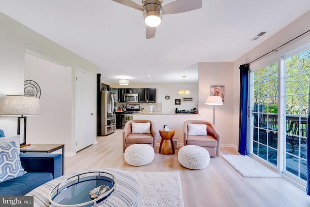 living room with light wood-style floors, baseboards, ceiling fan, and visible vents