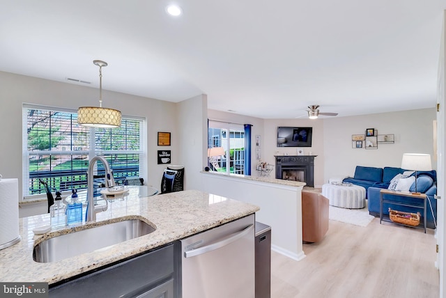 kitchen featuring stainless steel dishwasher, a ceiling fan, visible vents, a fireplace, and a sink
