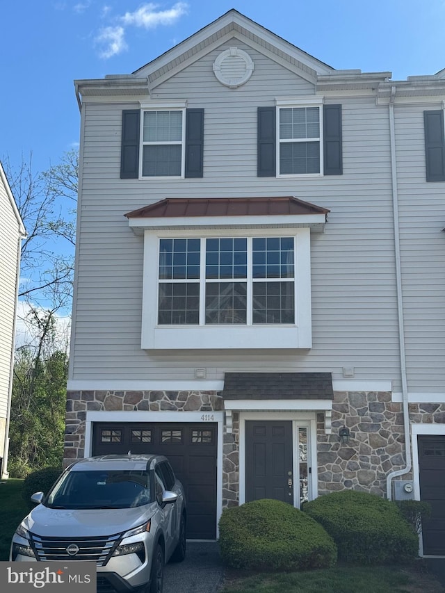 view of front of house featuring an attached garage and stone siding