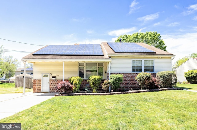 ranch-style house featuring roof mounted solar panels, concrete driveway, a front yard, and brick siding