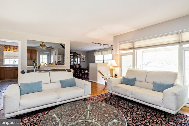 living room with rail lighting, light wood-style flooring, and ceiling fan with notable chandelier