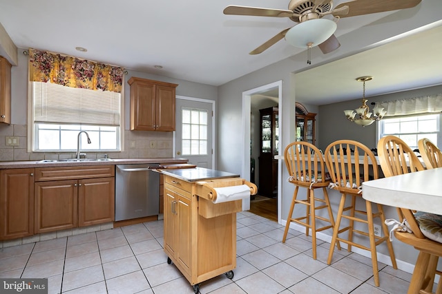 kitchen featuring decorative backsplash, dishwasher, light countertops, a sink, and light tile patterned floors