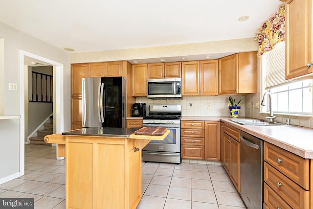 kitchen with a kitchen island, light tile patterned flooring, tasteful backsplash, a sink, and stainless steel appliances