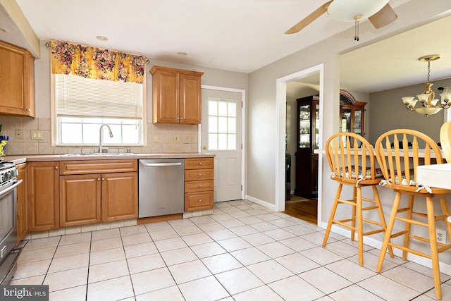 kitchen featuring a sink, light countertops, ceiling fan with notable chandelier, stainless steel appliances, and tasteful backsplash