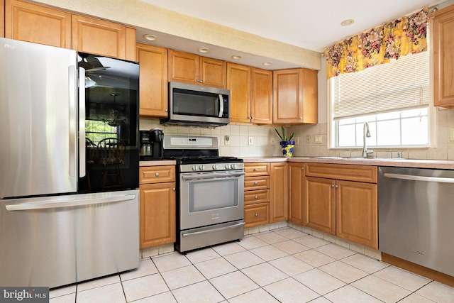 kitchen featuring light tile patterned flooring, a sink, stainless steel appliances, recessed lighting, and decorative backsplash