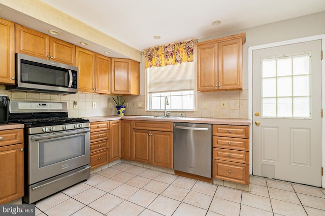 kitchen featuring decorative backsplash, appliances with stainless steel finishes, a sink, light tile patterned floors, and light countertops