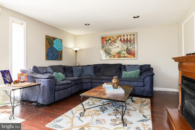 living area with recessed lighting, baseboards, a glass covered fireplace, and wood finished floors