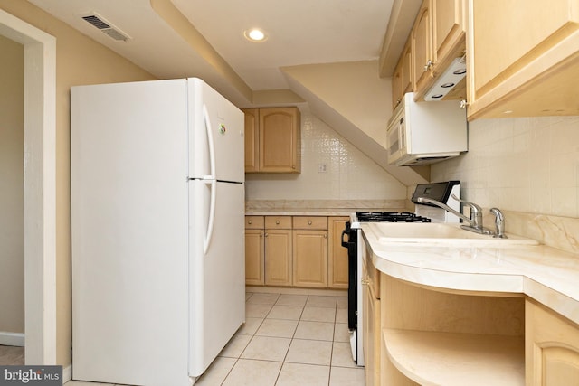kitchen featuring visible vents, light countertops, freestanding refrigerator, light brown cabinets, and gas range oven