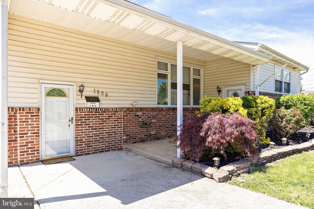 doorway to property featuring brick siding and a patio area