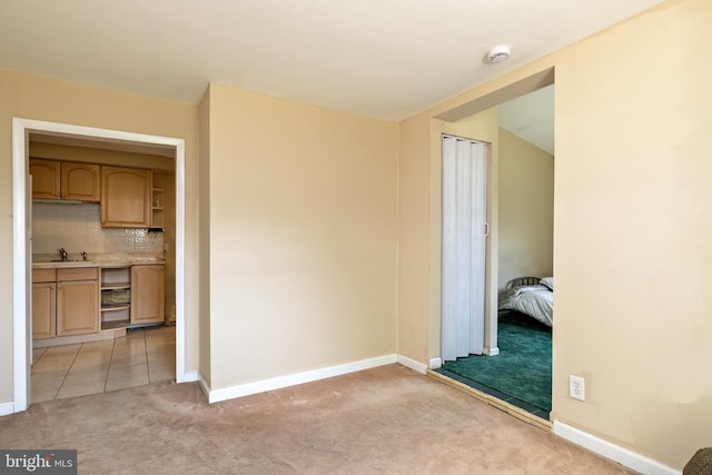 interior space with light colored carpet, a sink, and baseboards