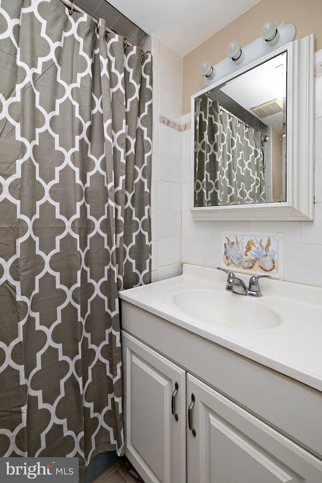 bathroom with vanity, tile walls, curtained shower, tasteful backsplash, and visible vents