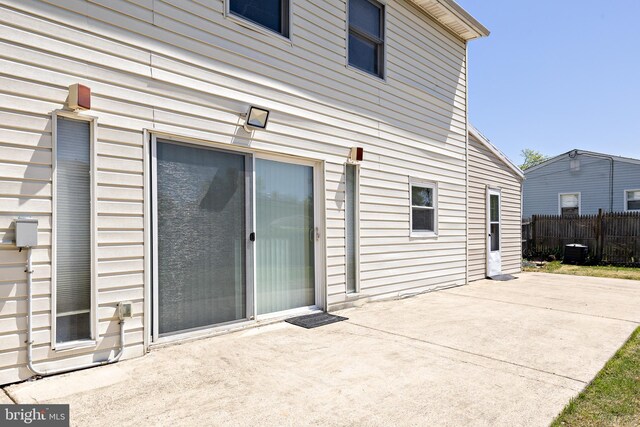 back of property featuring fence, a patio area, and central AC