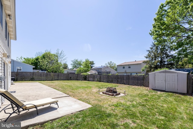 view of yard with a fire pit, a fenced backyard, a patio area, and a storage unit