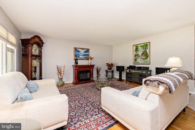 living room with a glass covered fireplace, baseboards, and wood finished floors
