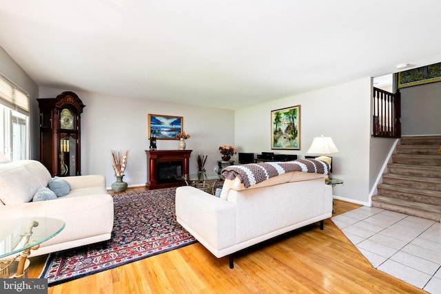 living area featuring baseboards, a fireplace, wood finished floors, and stairway