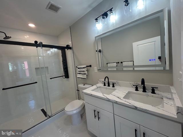 full bath with toilet, visible vents, a sink, and a stall shower