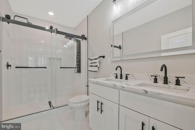full bath with double vanity, toilet, a shower stall, and a sink