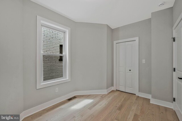 empty room featuring baseboards, light wood-type flooring, and visible vents