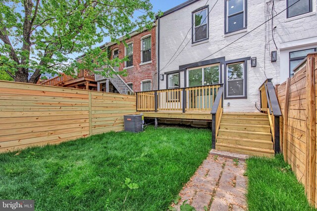 back of property featuring a fenced backyard, a wooden deck, a yard, and central air condition unit
