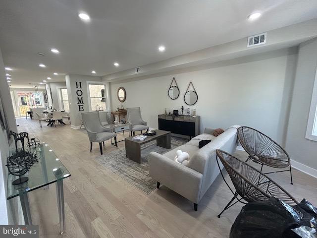 living area with baseboards, recessed lighting, wood finished floors, and visible vents