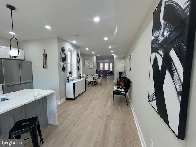 interior space with light stone countertops, baseboards, freestanding refrigerator, recessed lighting, and light wood-style flooring
