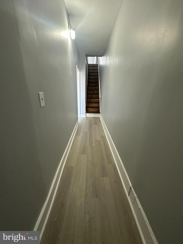 hall with baseboards, stairs, and wood finished floors