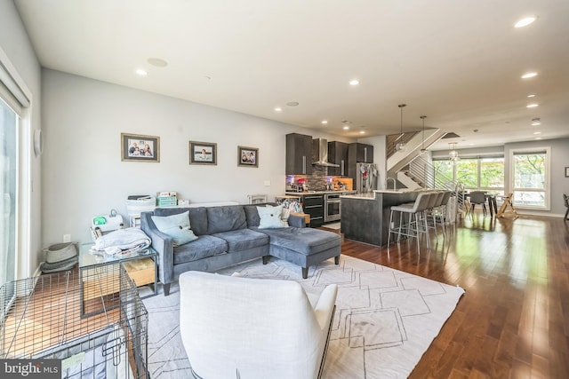 living area featuring recessed lighting, dark wood-style flooring, and stairs