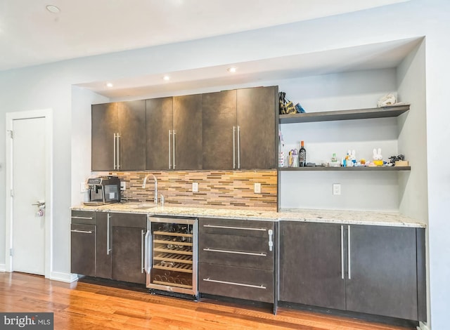 bar featuring indoor wet bar, wine cooler, tasteful backsplash, and light wood-type flooring
