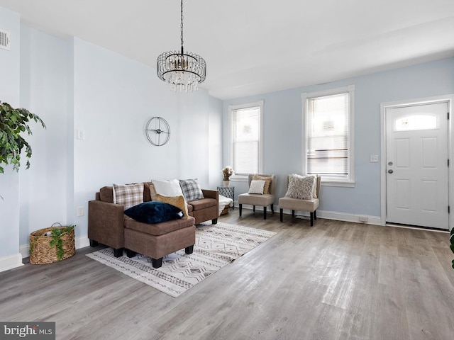living area with baseboards, a notable chandelier, and wood finished floors
