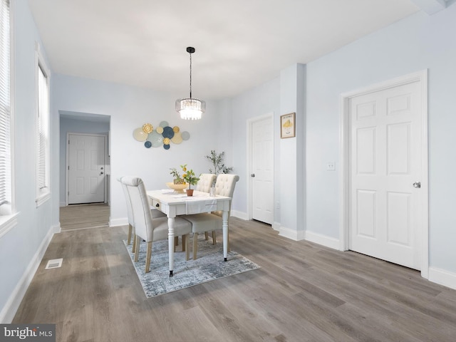 dining area featuring visible vents, baseboards, wood finished floors, and a chandelier