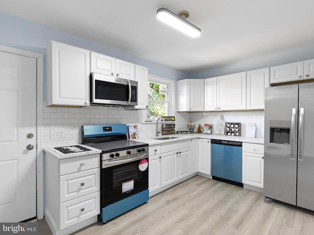 kitchen with white cabinets, appliances with stainless steel finishes, a sink, light wood finished floors, and light countertops