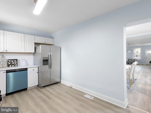 kitchen featuring visible vents, light countertops, stainless steel fridge, light wood finished floors, and dishwashing machine