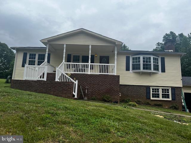 view of front of house featuring a front yard, brick siding, a chimney, and a porch