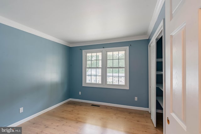 unfurnished room featuring wood finished floors, crown molding, and baseboards