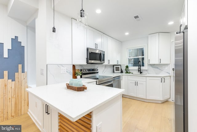 2074 E Birch St, Philadelphia, PA 19134 - kitchen with a peninsula, light wood-style floors, white cabinets, a sink, and stainless steel appliances