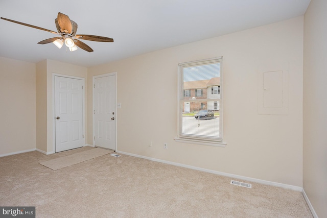 carpeted spare room with ceiling fan, baseboards, and electric panel