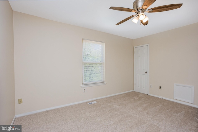 empty room with baseboards, light carpet, a ceiling fan, and visible vents
