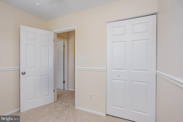 unfurnished bedroom with light colored carpet, baseboards, and a closet