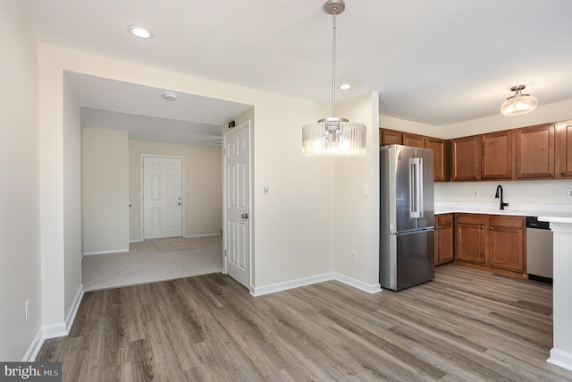 kitchen featuring appliances with stainless steel finishes, light countertops, brown cabinetry, recessed lighting, and light wood-type flooring