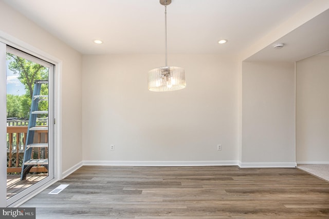unfurnished dining area with recessed lighting, baseboards, a notable chandelier, and wood finished floors