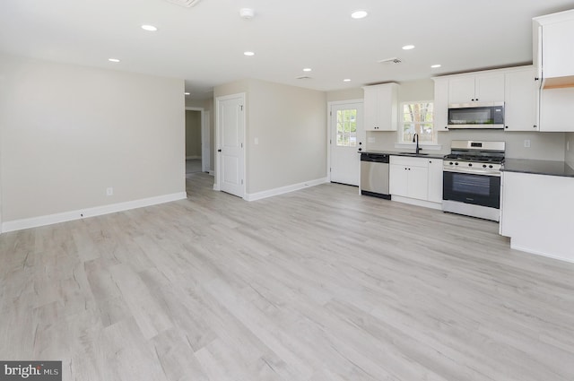 kitchen with a sink, appliances with stainless steel finishes, recessed lighting, and dark countertops