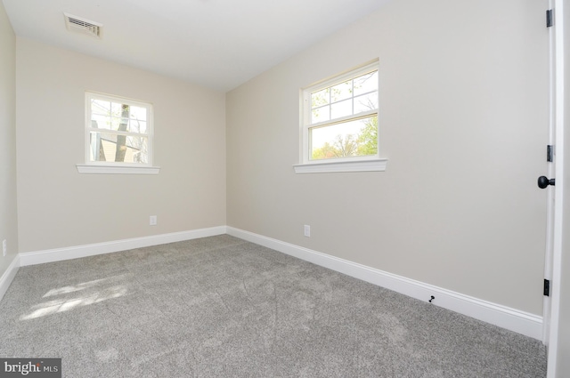carpeted spare room with visible vents and baseboards