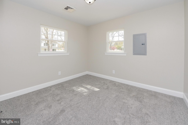carpeted empty room featuring baseboards, visible vents, and electric panel