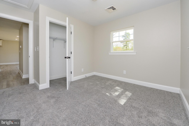 unfurnished bedroom featuring visible vents, carpet flooring, baseboards, and a closet