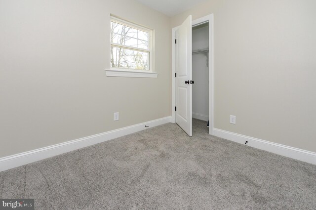 unfurnished bedroom featuring carpet floors, baseboards, a spacious closet, and a closet