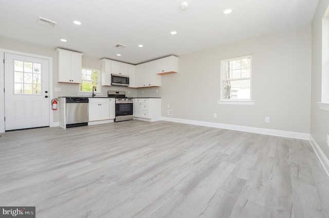 kitchen featuring visible vents, dark countertops, appliances with stainless steel finishes, light wood finished floors, and white cabinetry