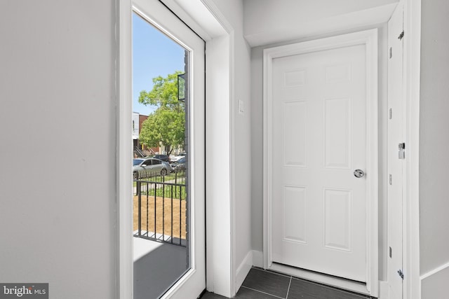 doorway to outside with baseboards, dark tile patterned floors, and a wealth of natural light