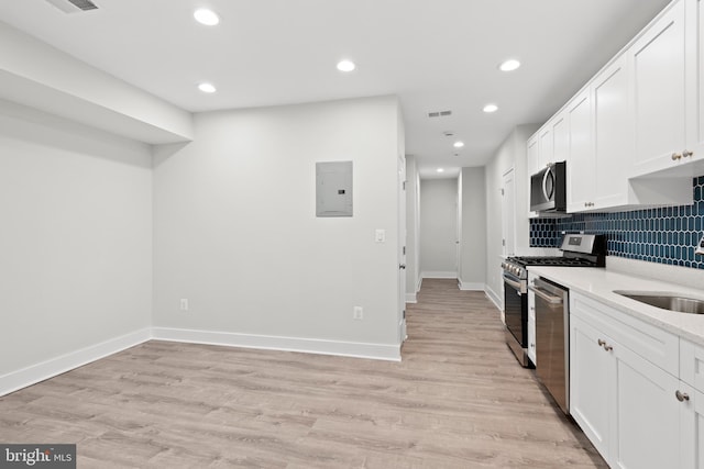 kitchen featuring white cabinets, stainless steel appliances, baseboards, recessed lighting, and backsplash
